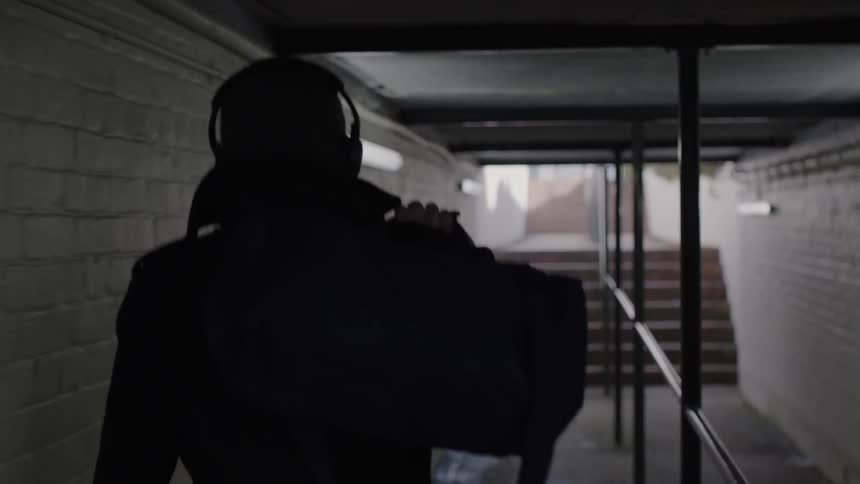 A man carries a bag up stairs while wearing headphones