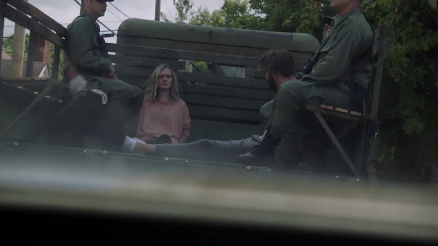 Soldiers ride in the back of a truck with prisoners