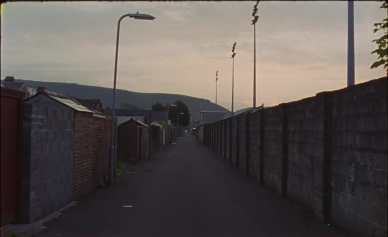 Long pathway sits next to a fence under a cloudy sky