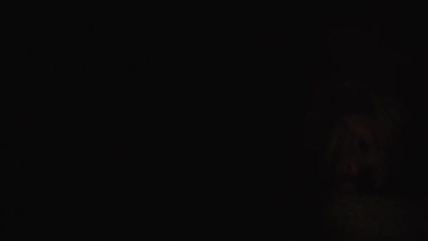 A woman is laying on the ground in the dark