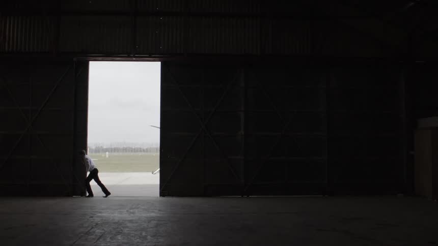 Man opening airplane hangar door