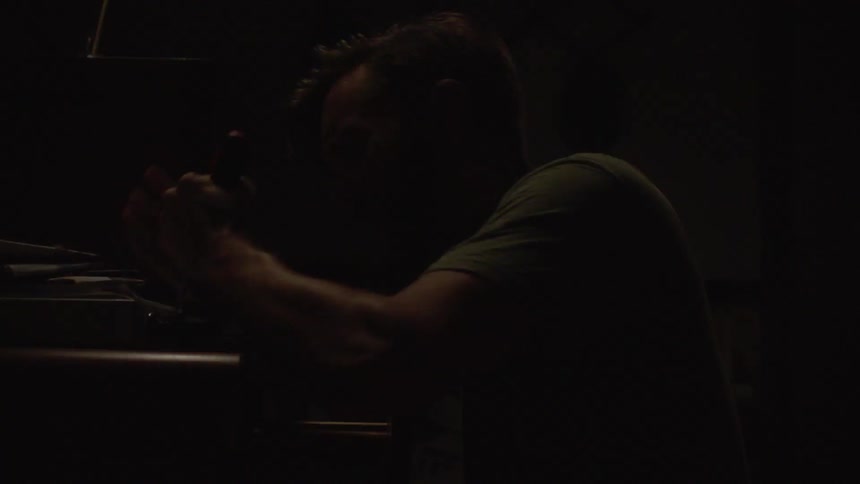 A frantic man raises his hands as the police enter the room