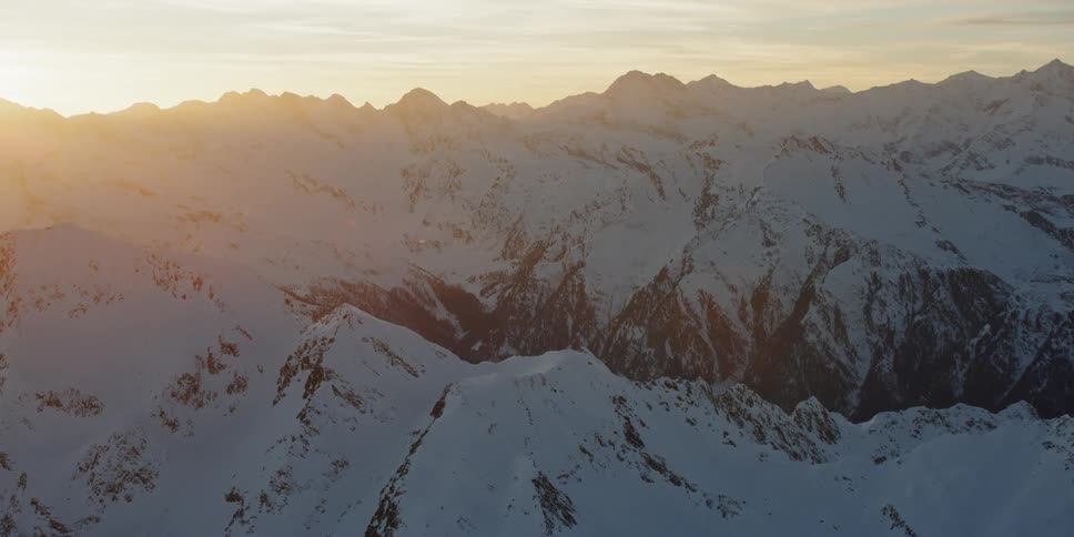 The sun shines on snow covered mountain ridges