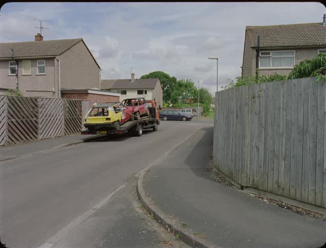 Junk cars on a truck parked in front of a house