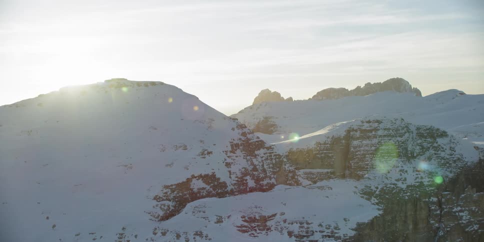 The sun sets over snowy mountains