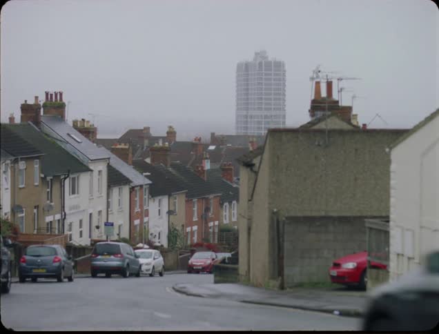 People and cars travel uphill in town