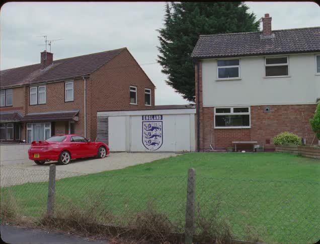 A red car is parked in front of the house