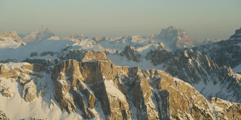 The sun shines on snow covered jagged ridges with mt. Pelmo in the background
