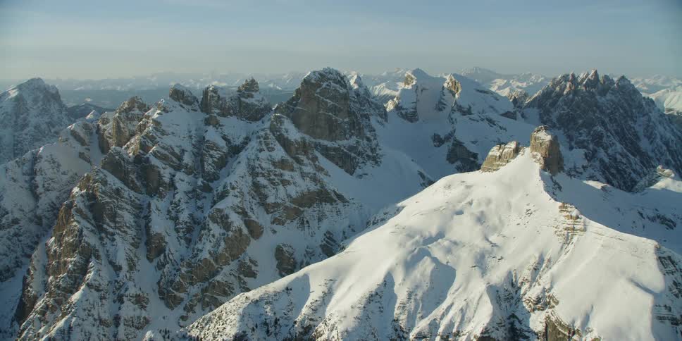 Snow is covering the slopes of a mountain range during the day