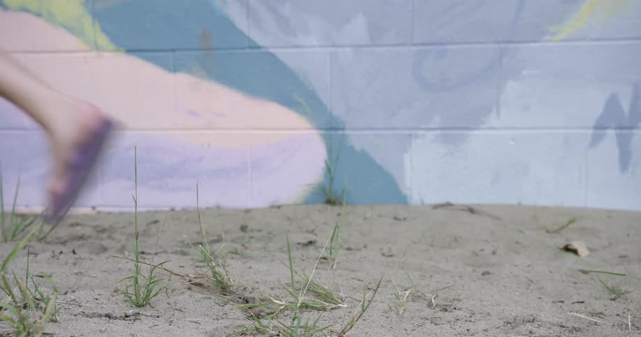 People walk in sand near a wall