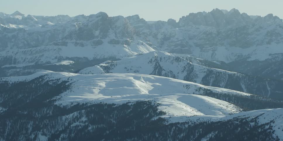 The hills are covered with heavy snow and tall trees