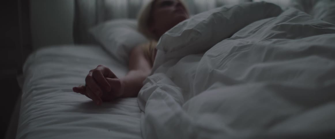 A woman is laying in bed playing with the ring on her finger