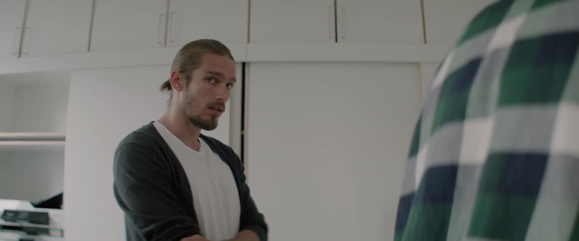 A man is talking to another person as they stand inside in daylight