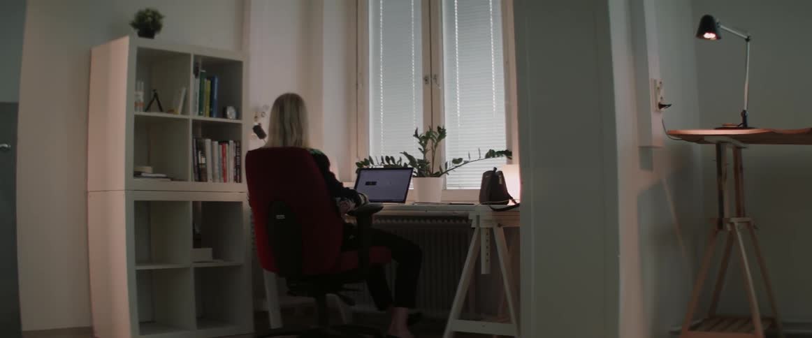 A woman sitting at a desk is pushing her chair back then typing on her computer