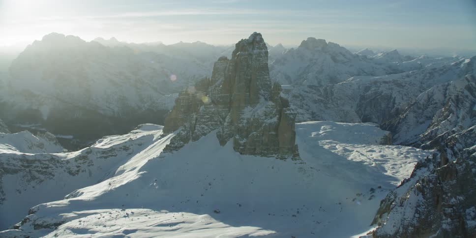 Mountain peaks are casting shadows in the snow during the day