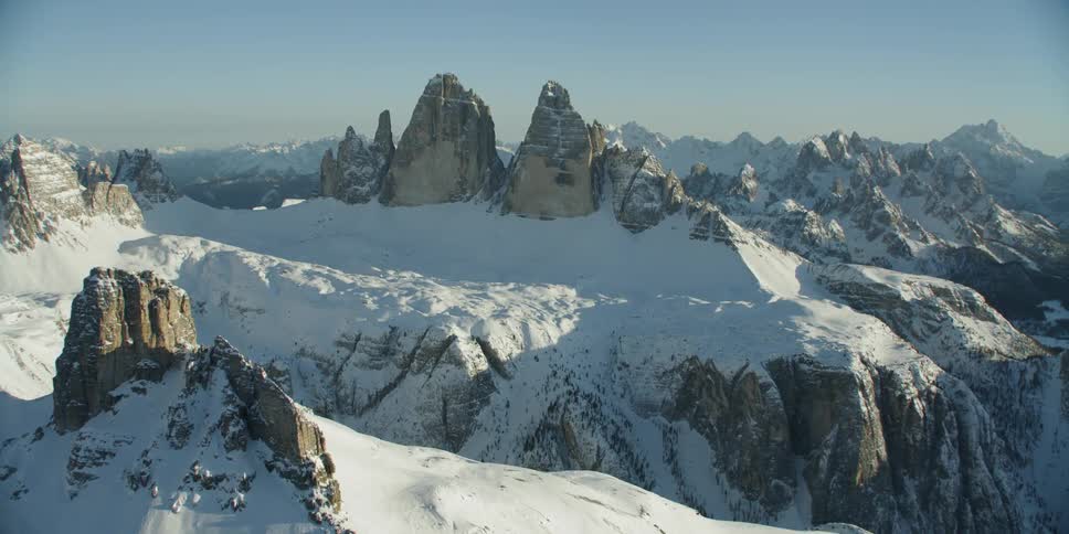 Mountain peaks are casting shadows in the snow during the day