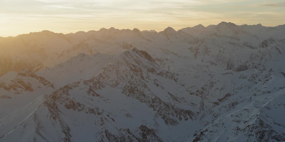 Sunlight is streaming onto a mountain range covered in snow at dawn