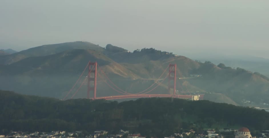 A red bridge lies behind a city