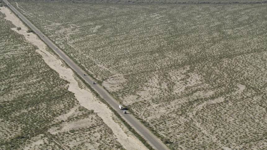 Vehicles travel down a long desert highway
