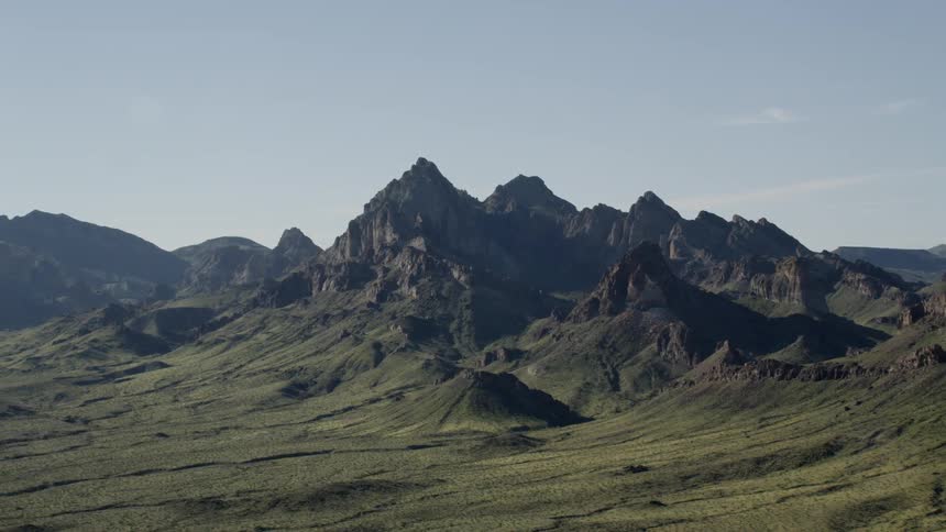 The green hills lead to pointy mountains