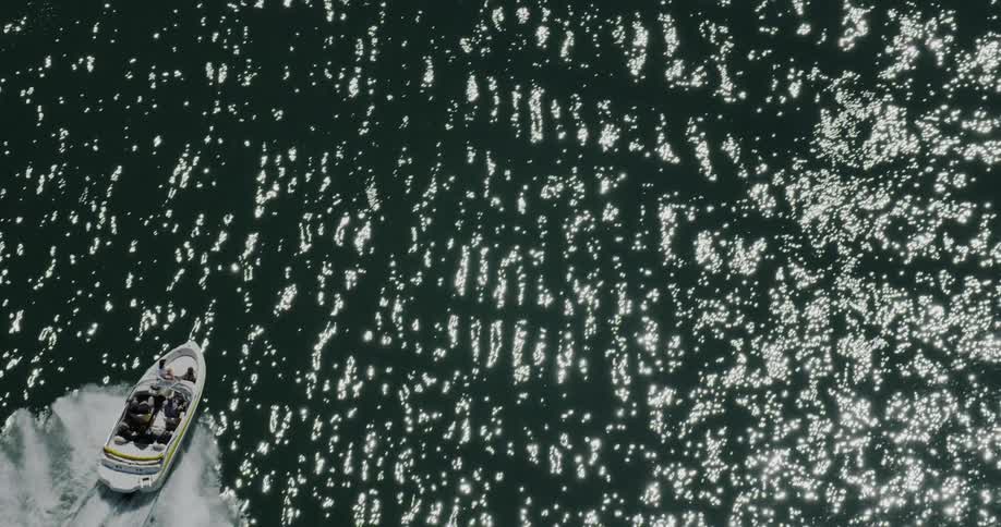 A boat races on top of a glimmering lake