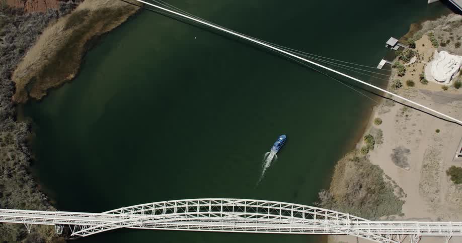 Boat passes under tall spanning bridges in the Colorado River