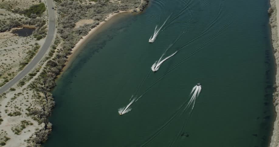 Different boats travel in the lake in opposite directions