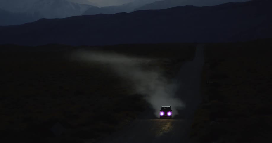 An suv kicks up dust as it travels on a dirt road