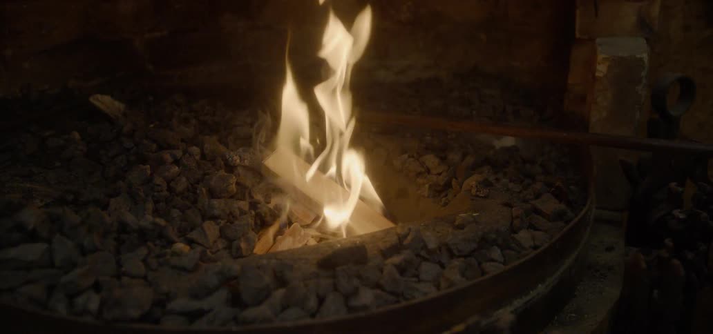 A person stirs the rocks in the fire