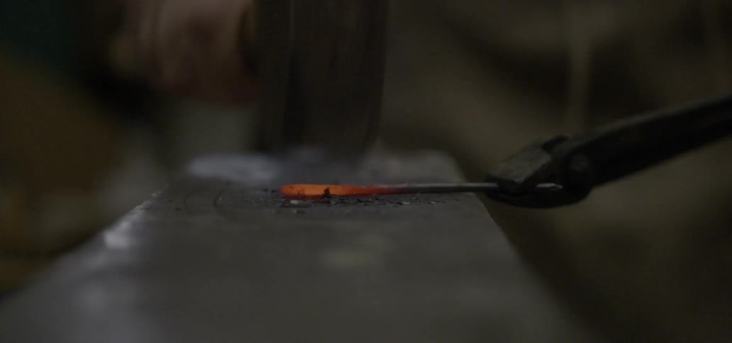 A blacksmith hammers a piece of metal