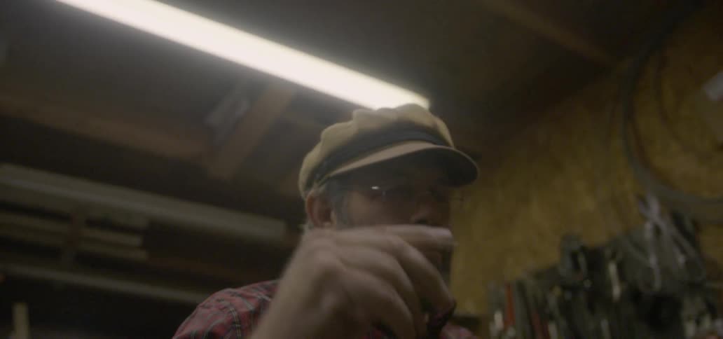 A man removes his hat in a workshop
