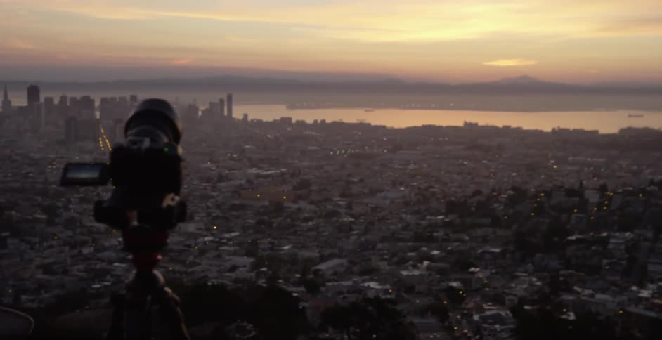 Shot of a camera pointed out over a city located next to the ocean during a cloudy sunset