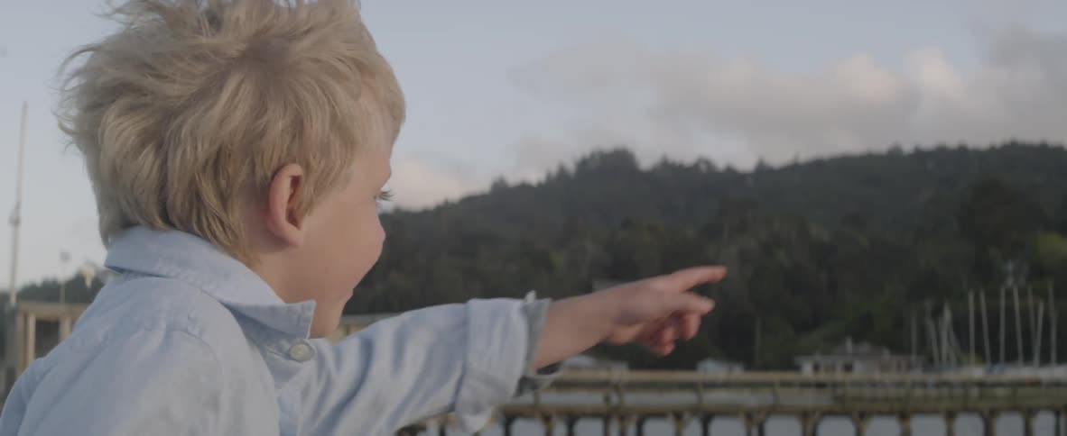 A child is pointing out over the water before running