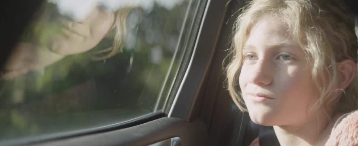 Child sits in in a vehicle looking out a window