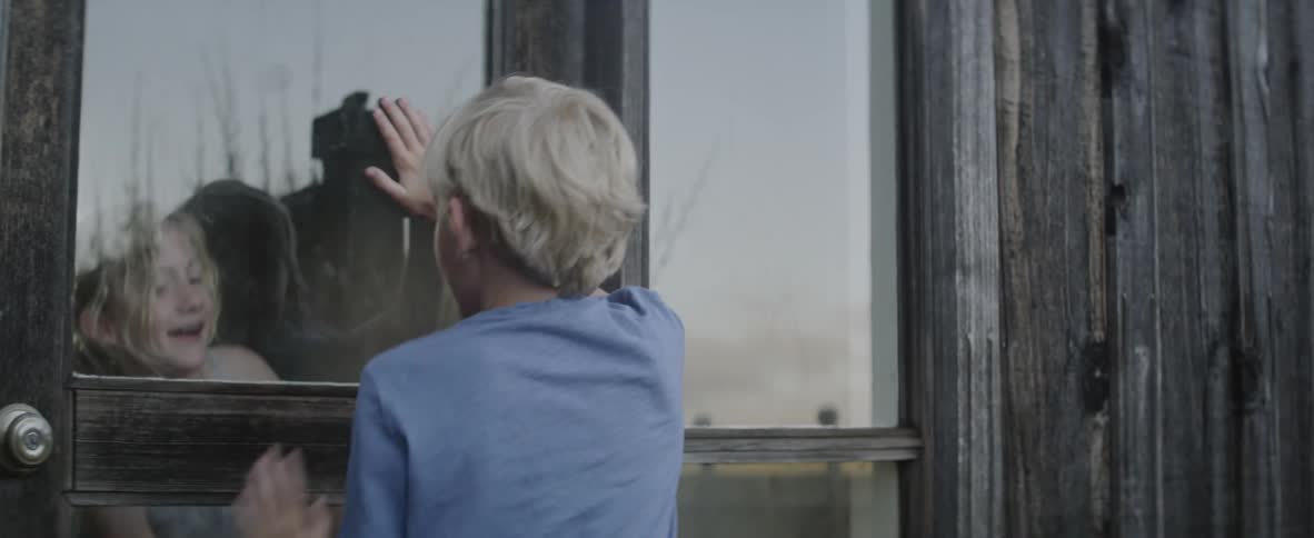 A boy and girl play next to a window