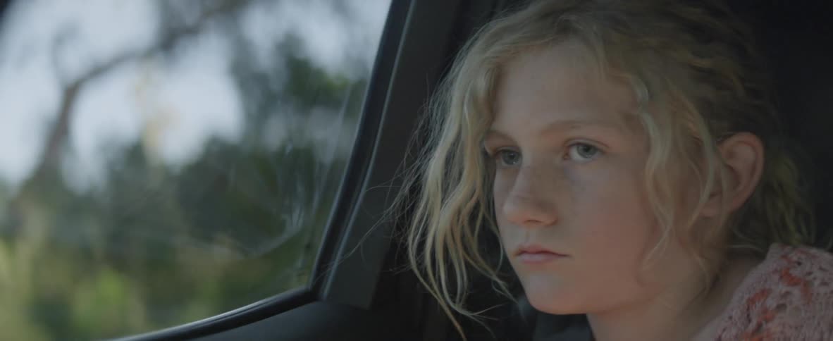 A girl looks out the window of a traveling car