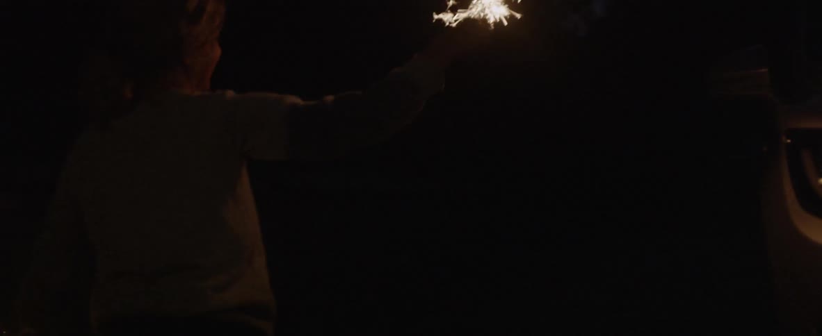 Children run around with burning sparklers in the dark