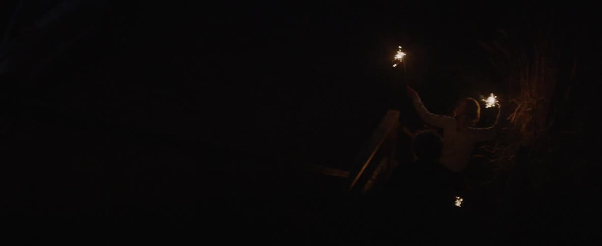The children dance and swing sparklers at night