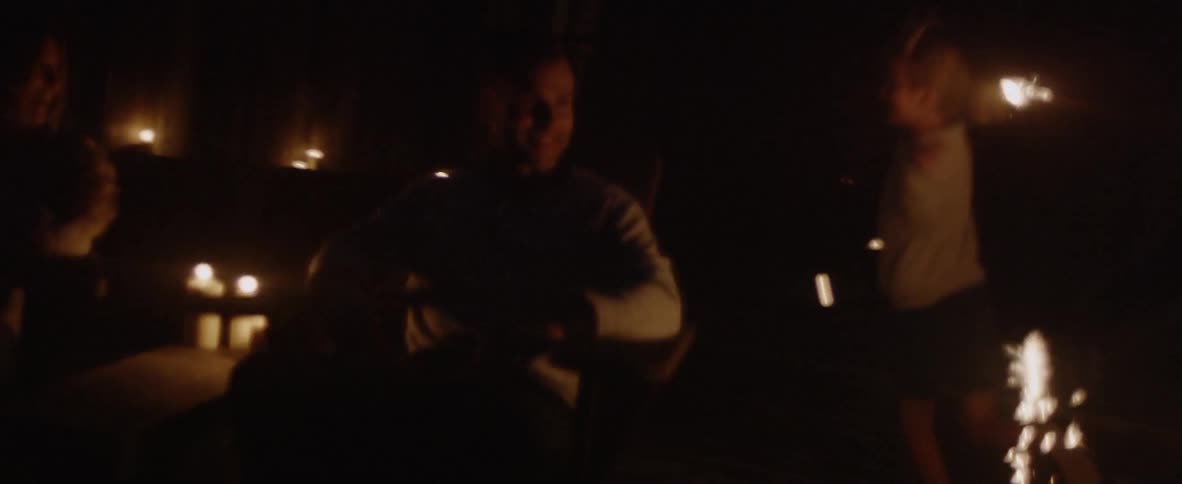 The children run around the parents waving sparklers at night