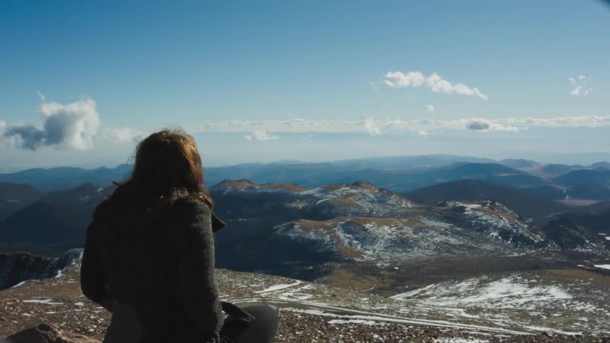 Woman standing on top of a mountain looking over