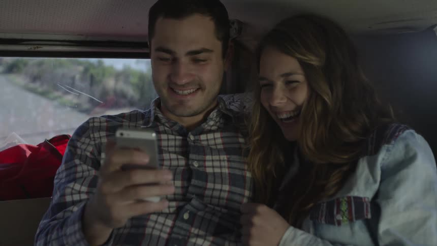 Man and woman look at a phone together in a vehicle