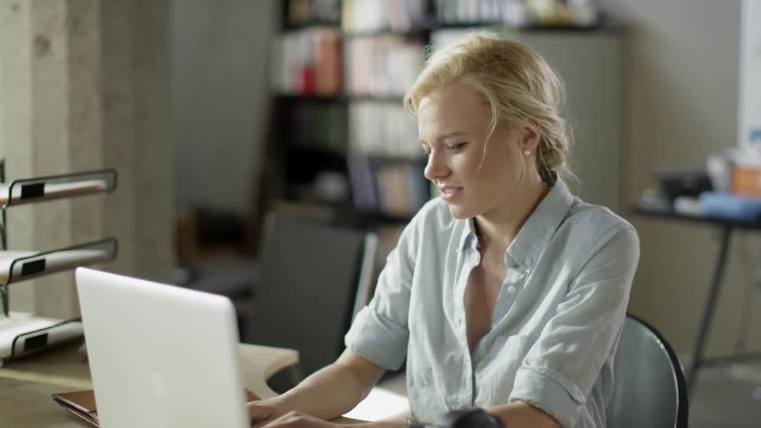 A blonde woman opening a laptop