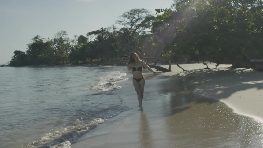 A woman in a bikini walks by the water
