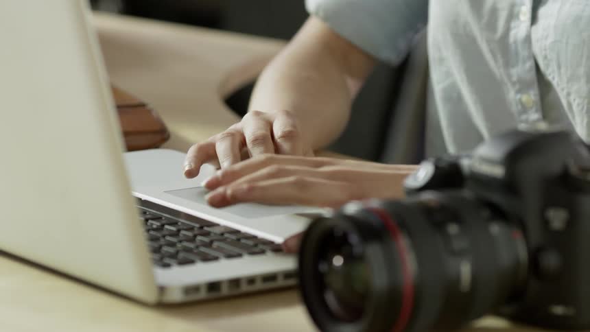 A young, blonde woman smiling and typing on a laptop