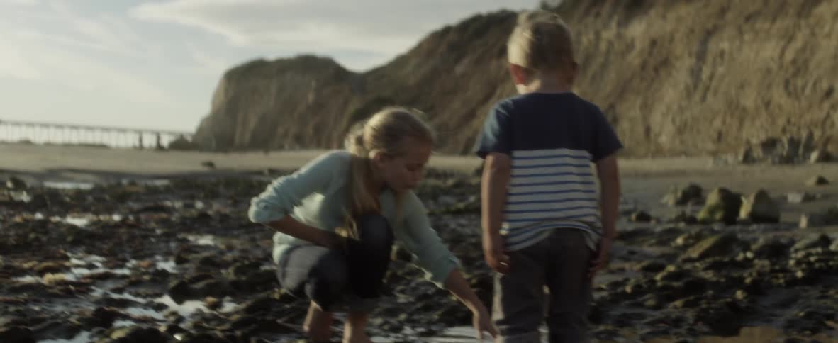 Child walks over to a girl playing in the water