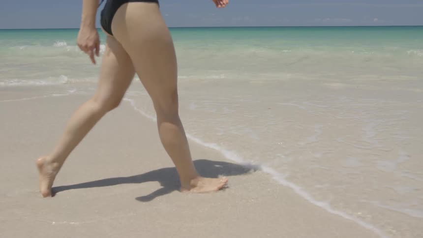 A woman walks through the water on the beach