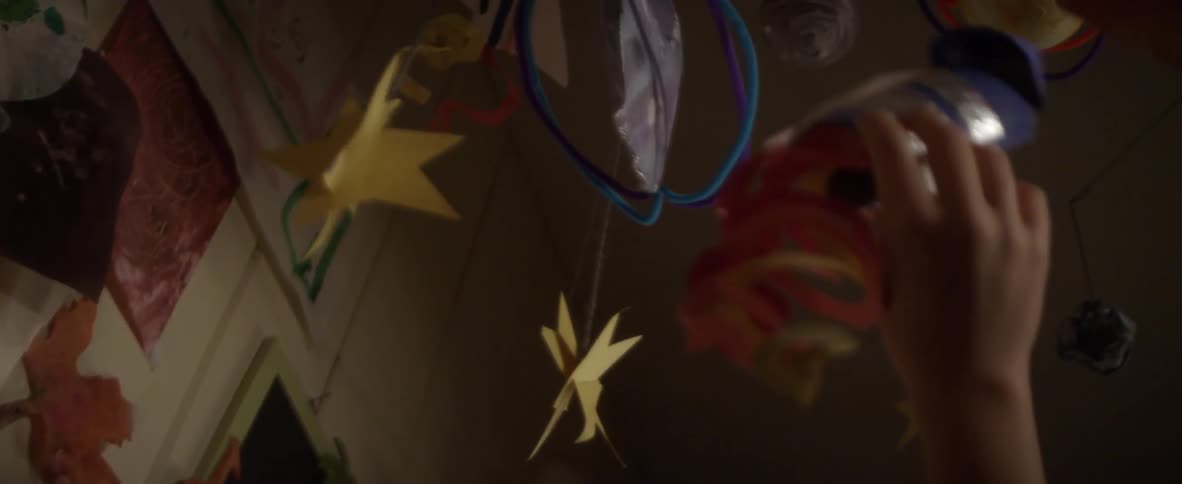 Hand moving a toy across hanging ornaments