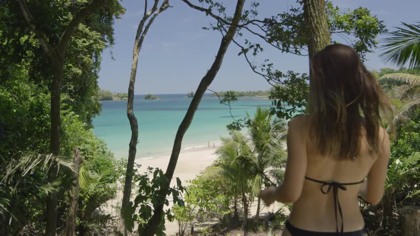 Woman walks on a beach in a bikini