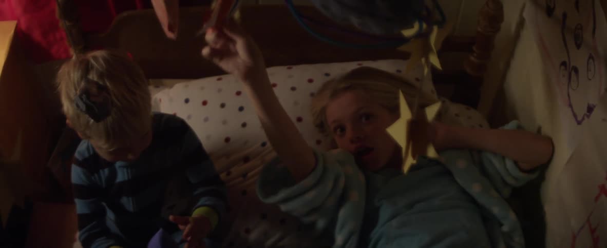 Two children in a bed pretending to fly rockets