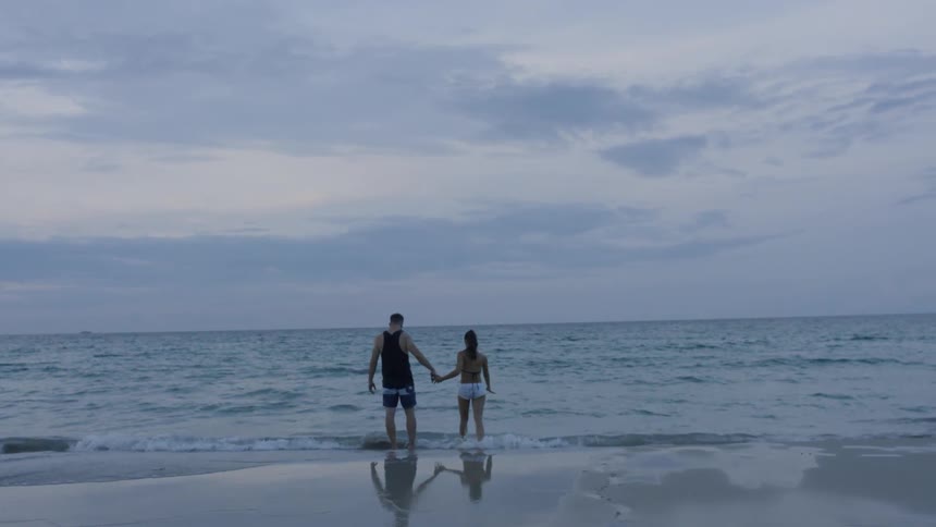 A man and woman walk into the water
